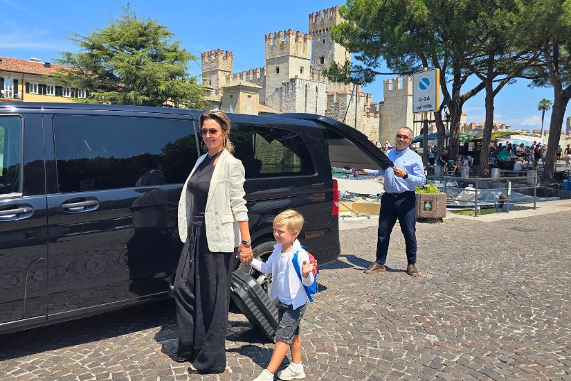 A BookTaxi driver helps tourists get out of the Mercedes in the historic centre of Sirmione