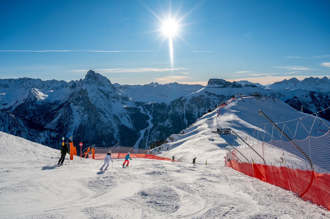Skifahrer auf einer präparierten Piste in den Dolomiten vor verschneiten Gipfeln